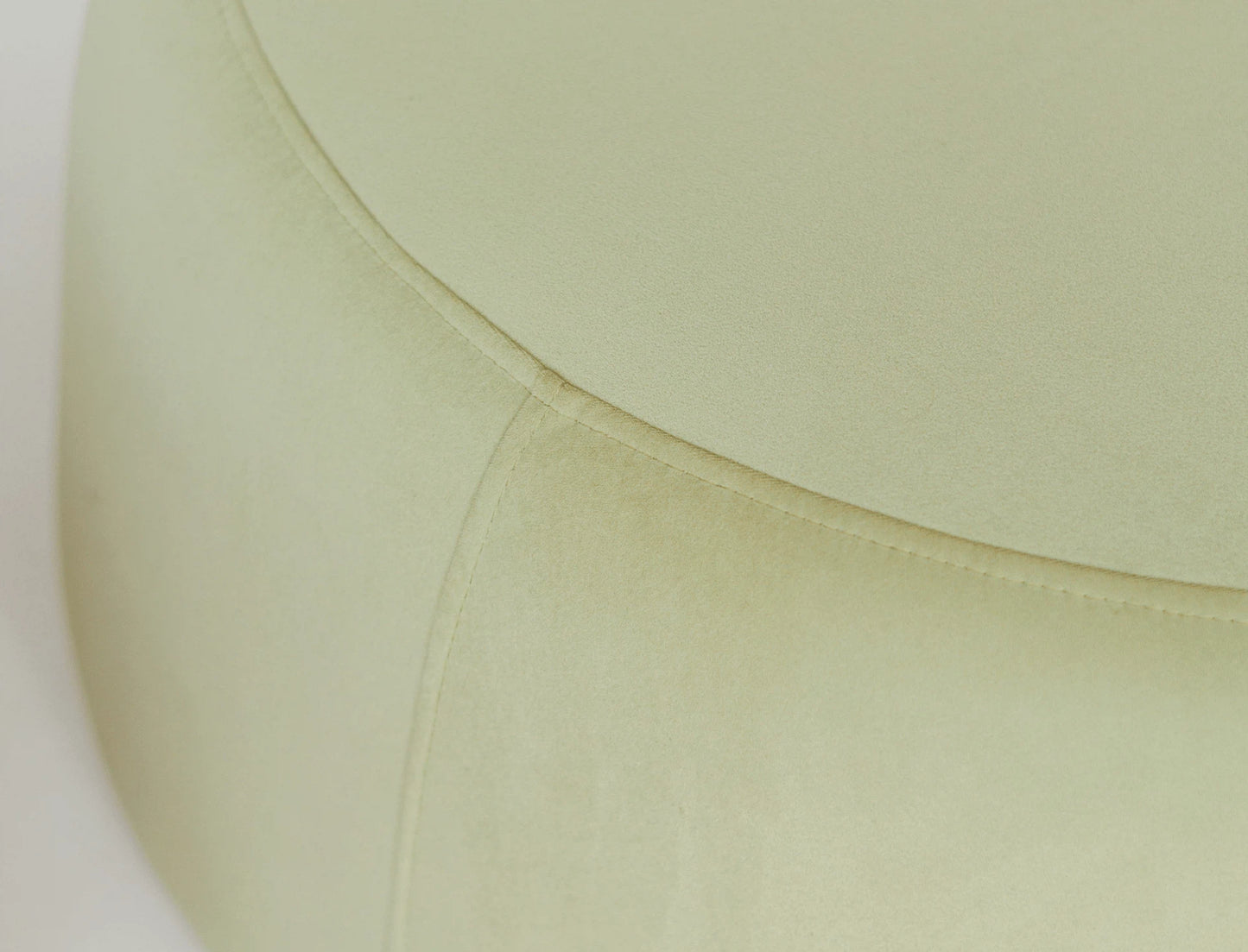 Close up of a round green velvet ottoman. 