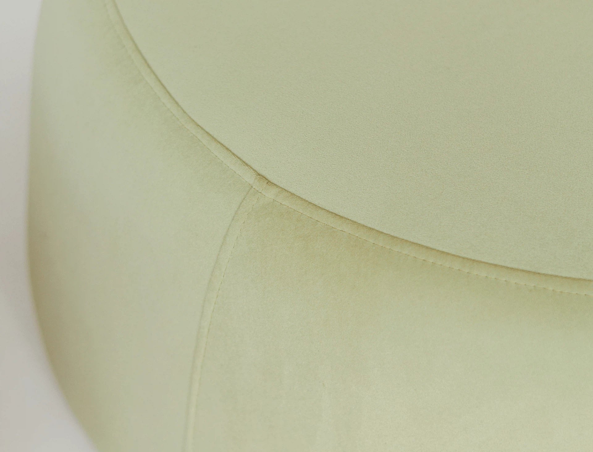 Close up of a round green velvet ottoman. 