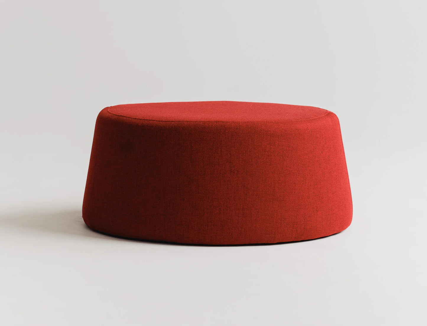 Round red ottoman on a light gray background