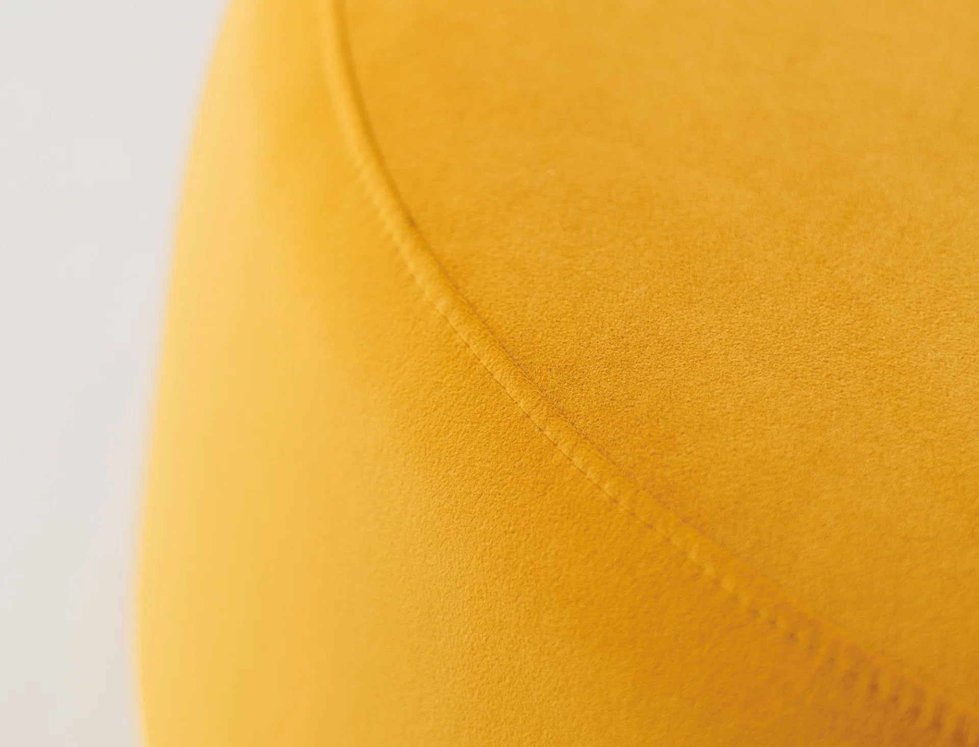 Close-up of a yellow velvet round ottoman. 