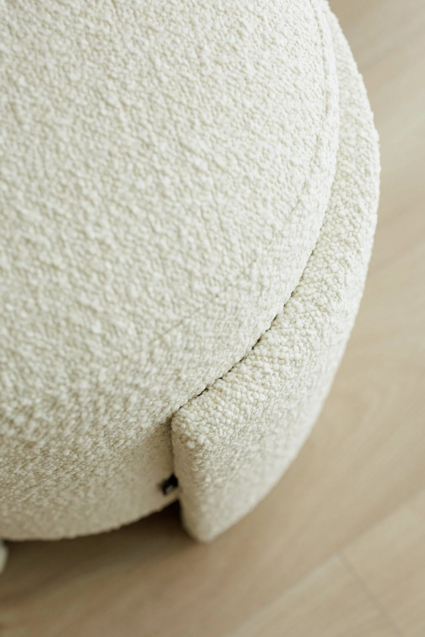 Close-up of a textured white boucle pouf on a neutral background
