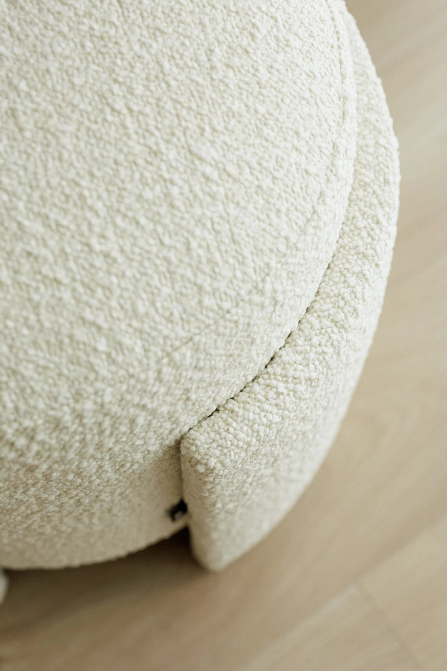 Close-up of a textured white boucle pouf on a neutral background
