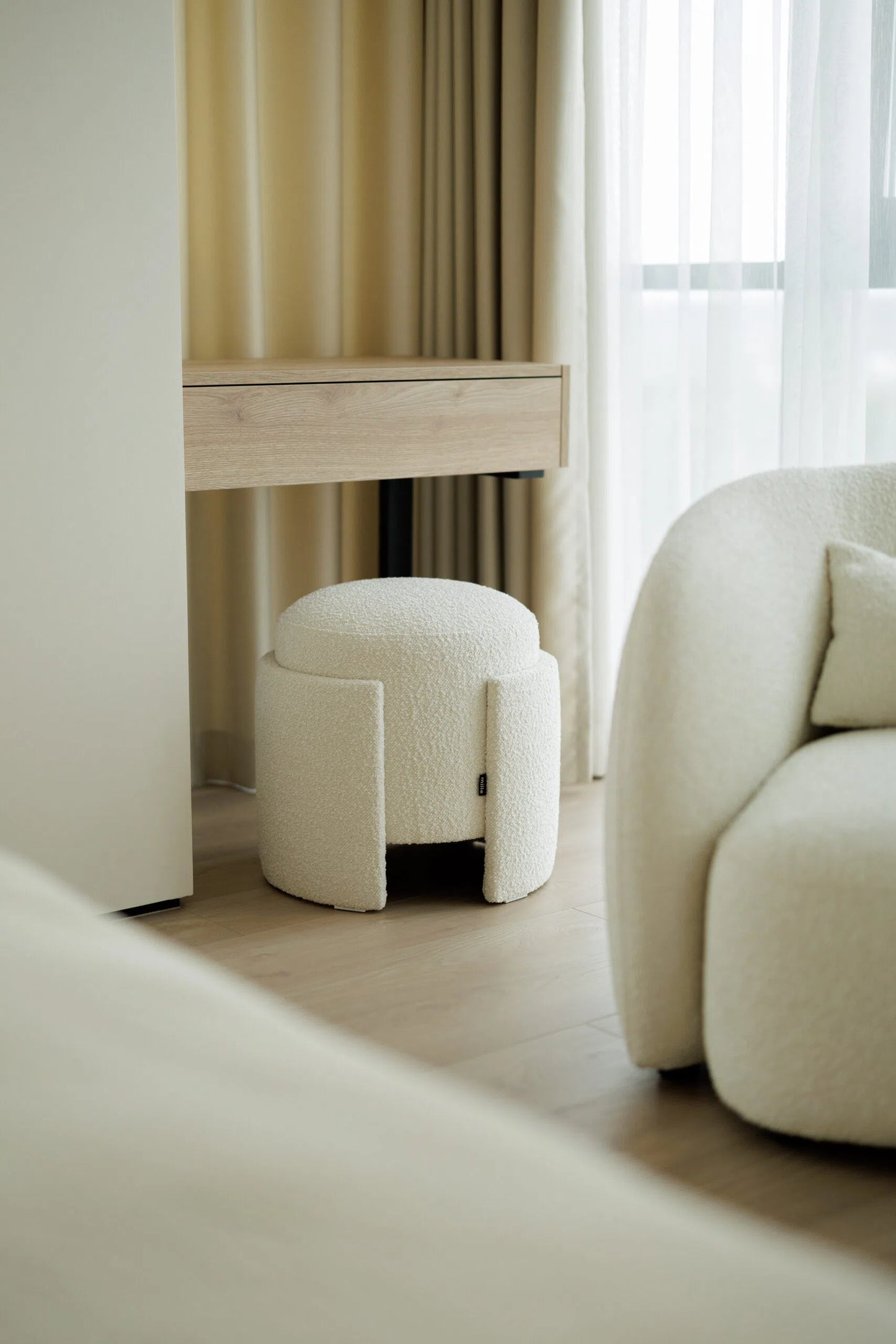 White textured ottoman in a room with a desk and curtains