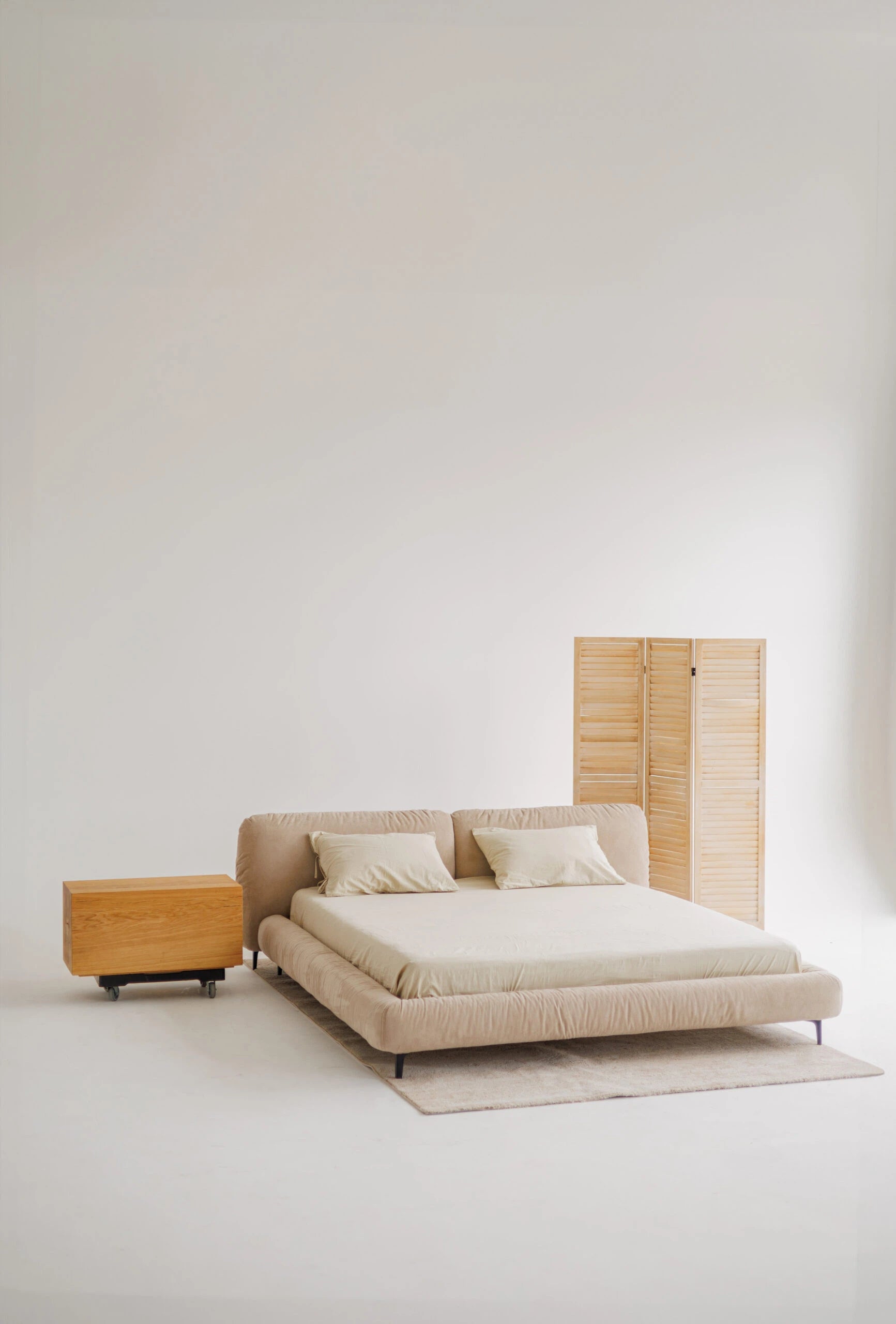 Modern designer bed with interesting headboard and wooden side table against a white wall