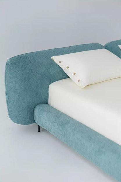Blue luxury bed with white bedding on a light gray background