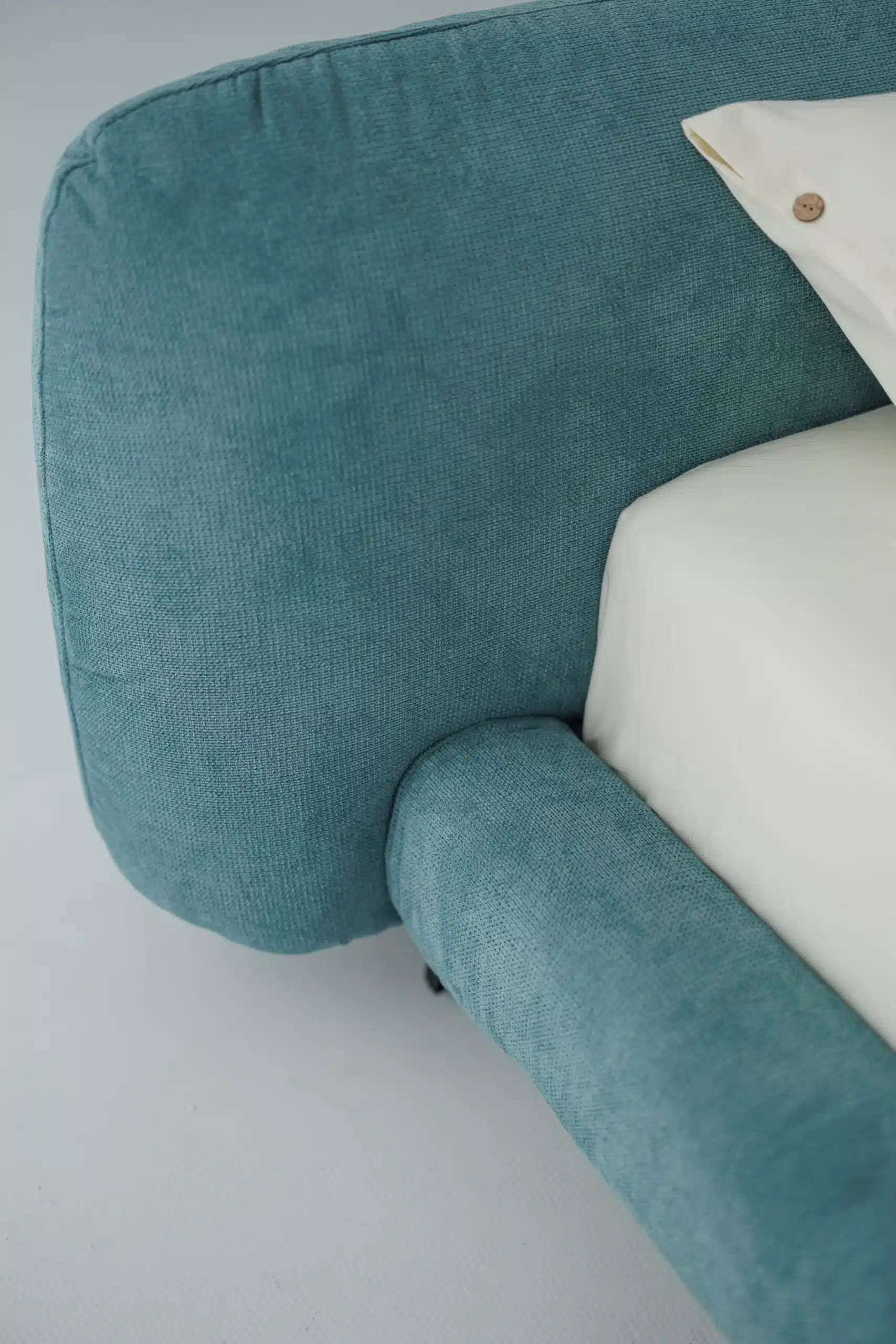 Blue upholstered bed with a white bedding on a light gray background