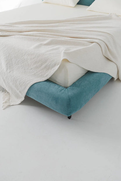 Blue bed frame with white bedding on a light gray background