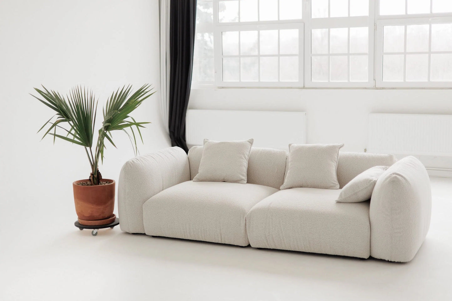 White sofa in a room with a large window and a plant.