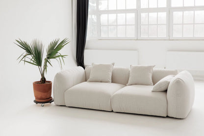White sofa in a room with a large window and a plant.