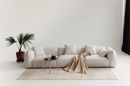 White modular sofa with a blanket and small table in a minimalistic living room.