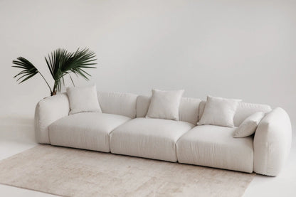 White luxury sofa in a minimalistic room with a plant and rug.