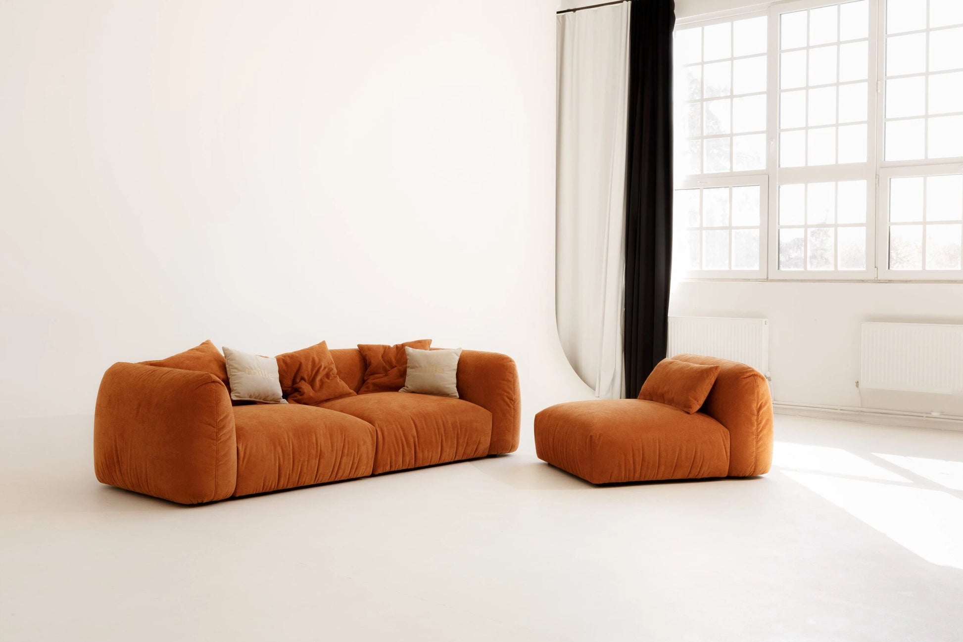 Orange sofa and armchair in a bright room with large windows