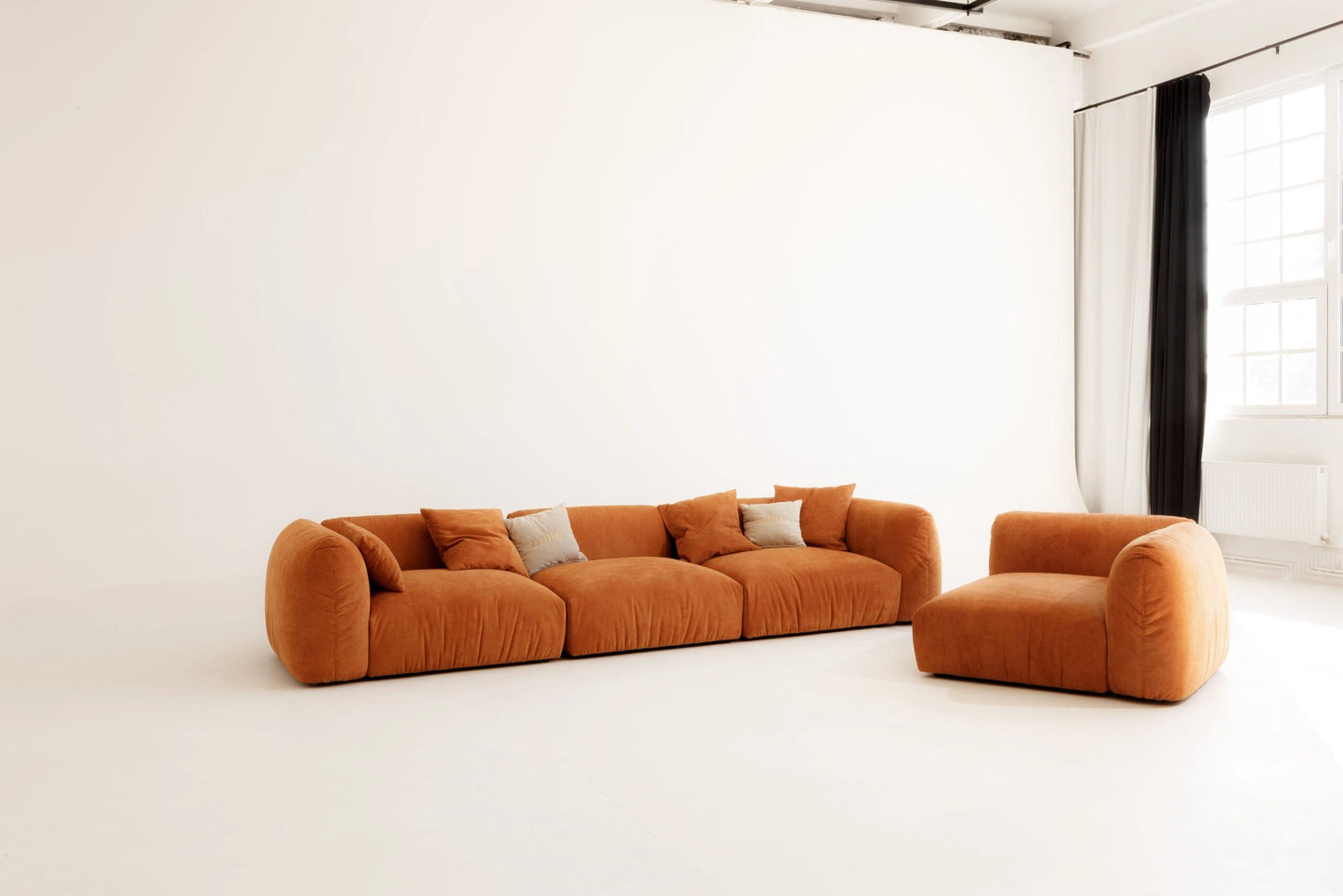 Orange modular sofa set in a minimalistic room with white walls and floor.