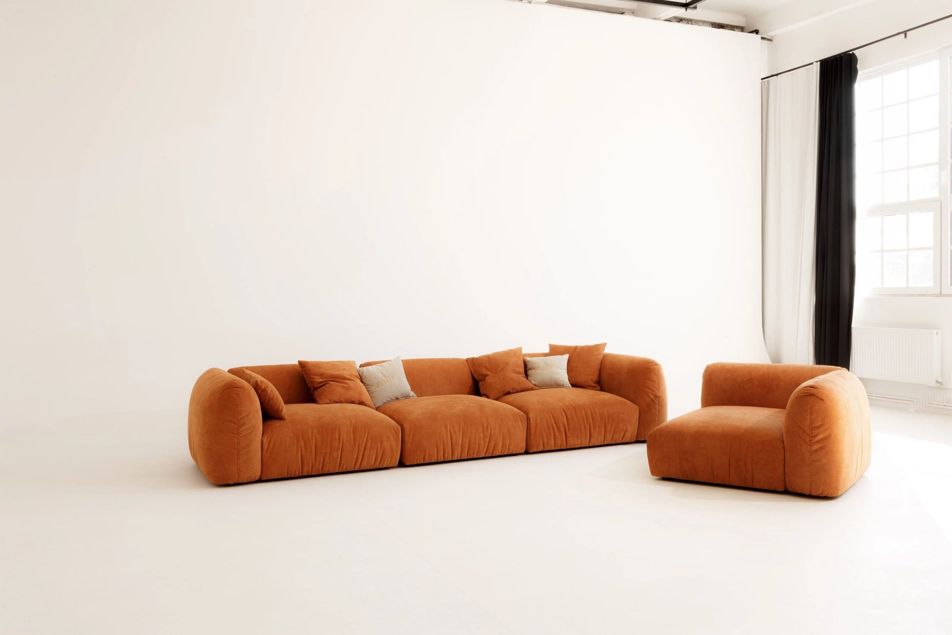 Orange modular sofa set in a minimalistic room with white walls and floor.