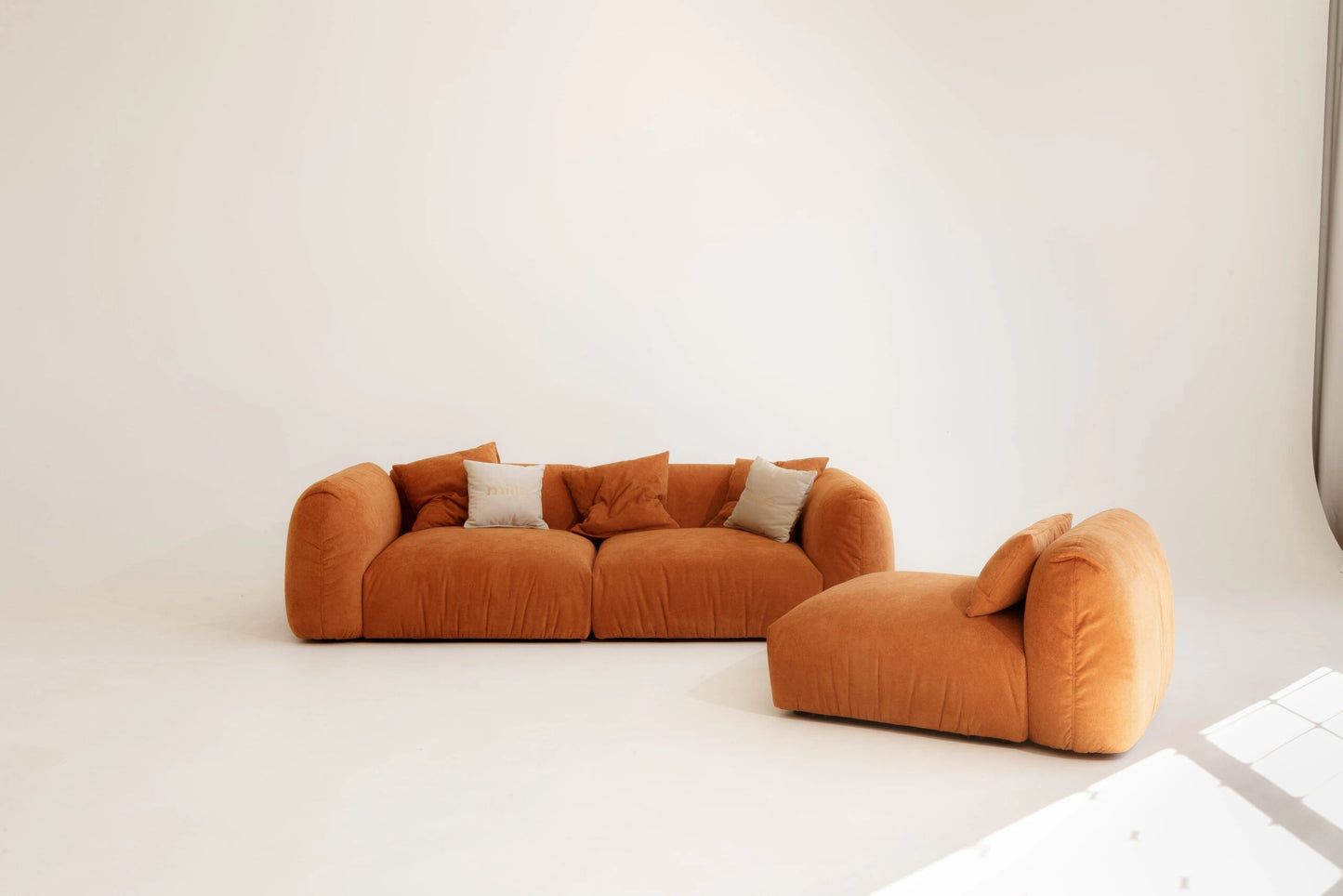 Orange sofa with modular design with two cushions on a white background