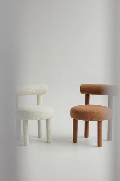 Two upholstered bouclé chairs, one white and one brown, on a light gray background