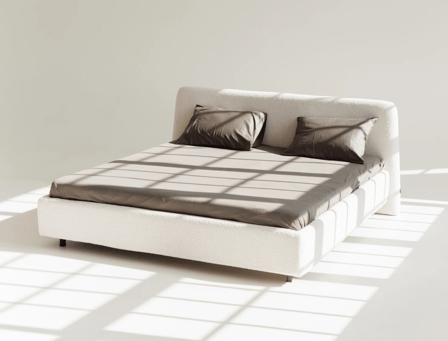 White bed with gray bedding in a minimalistic room